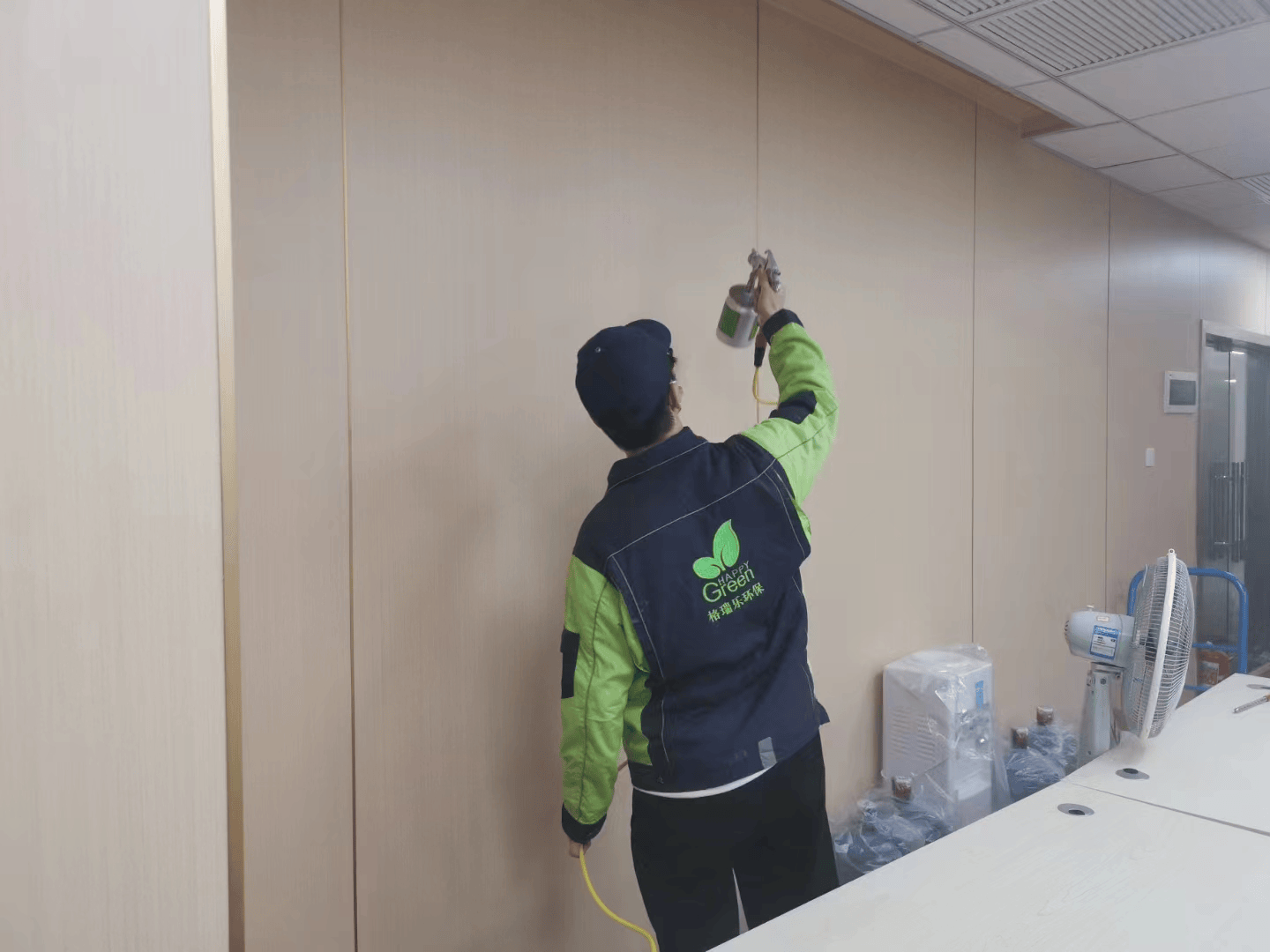 阁楼里，施工人员在狭窄空间内相互协作，一人在有限的空间中操作工具对家具进行除醛处理，另一人在旁边提供照明和协助传递材料，共同完成家具的除醛工作。